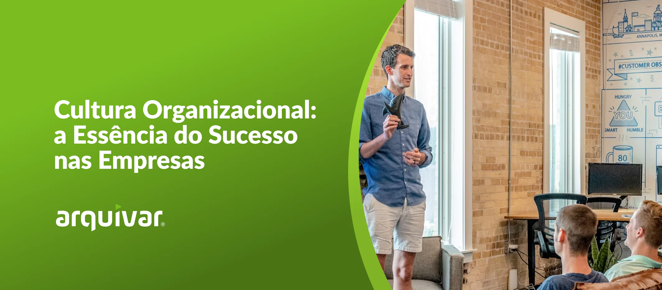 Grupo de homens profissionais se reúne em ambiente empresarial com banner com os dizeres de vendas para ilustrar o tema cultura empresarial. De pé, o CEO de uma empresa palestra para a equipe.